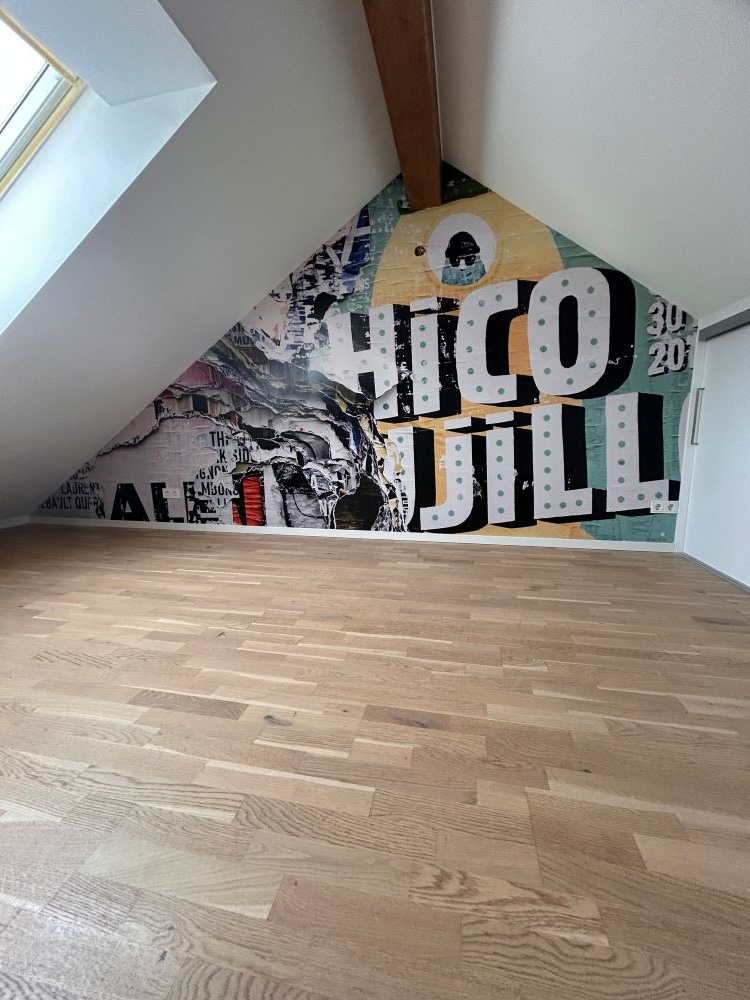 Zimmer mit Dachschrägen und einer künstlicherisch bemalten Wand