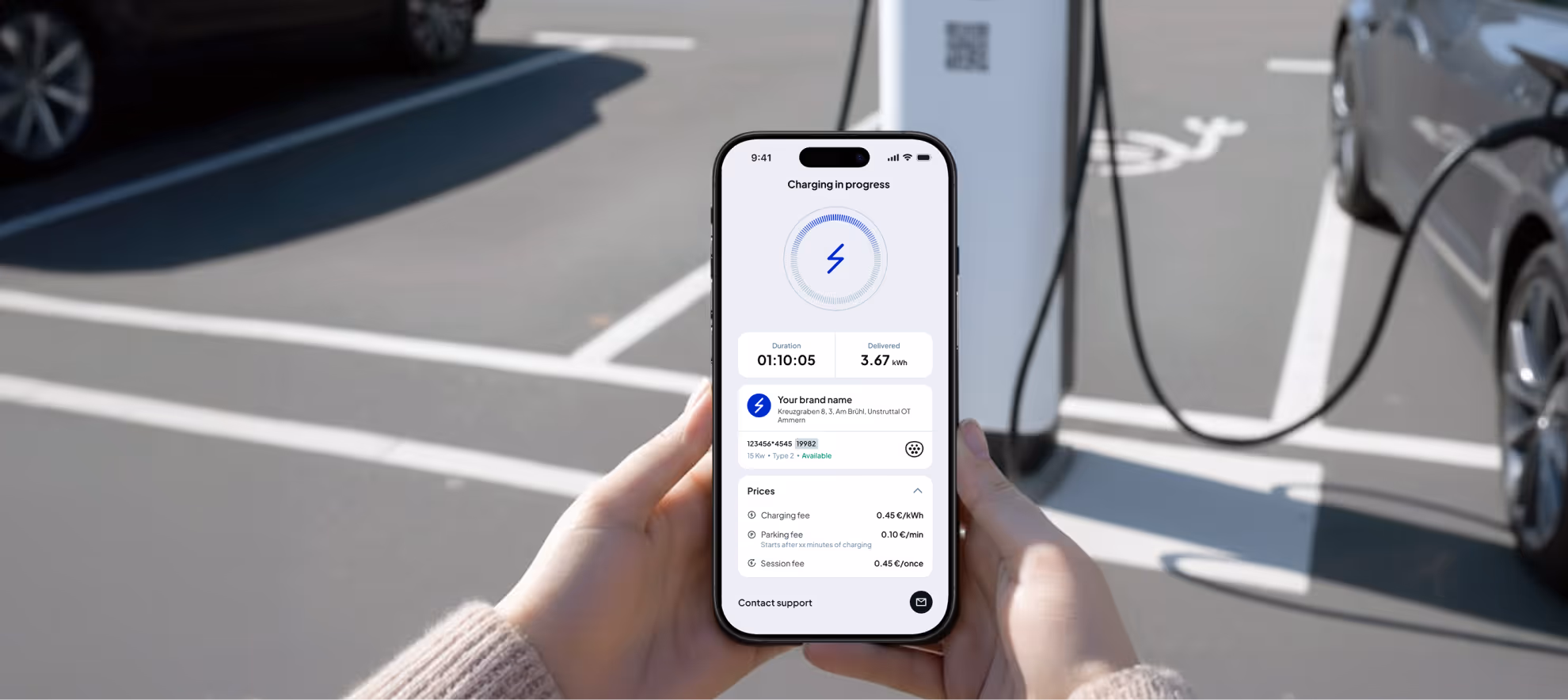 Person holding a smartphone showing an electric vehicle charging app with charging progress and pricing details, next to a car plugged into a charging station.