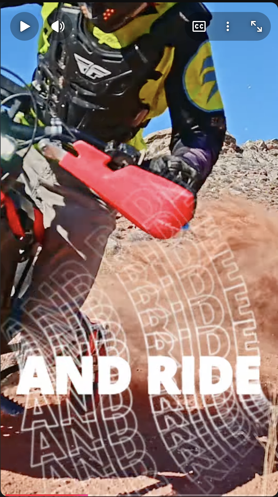 Close-up of a mountain biker wearing protective gear riding on rocky terrain with dust rising.