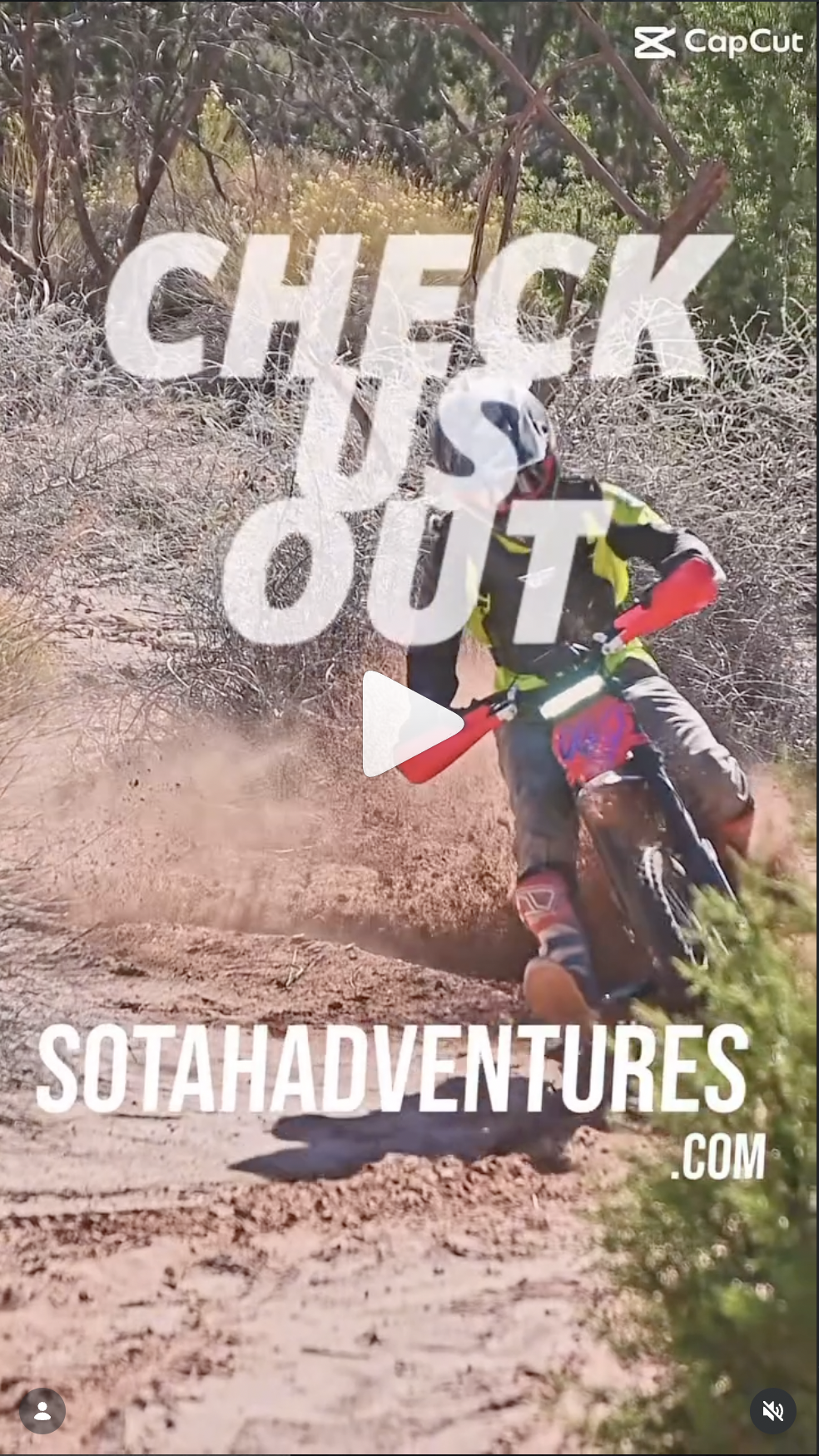 Person riding a dirt bike on a dusty trail surrounded by dry bushes and trees.