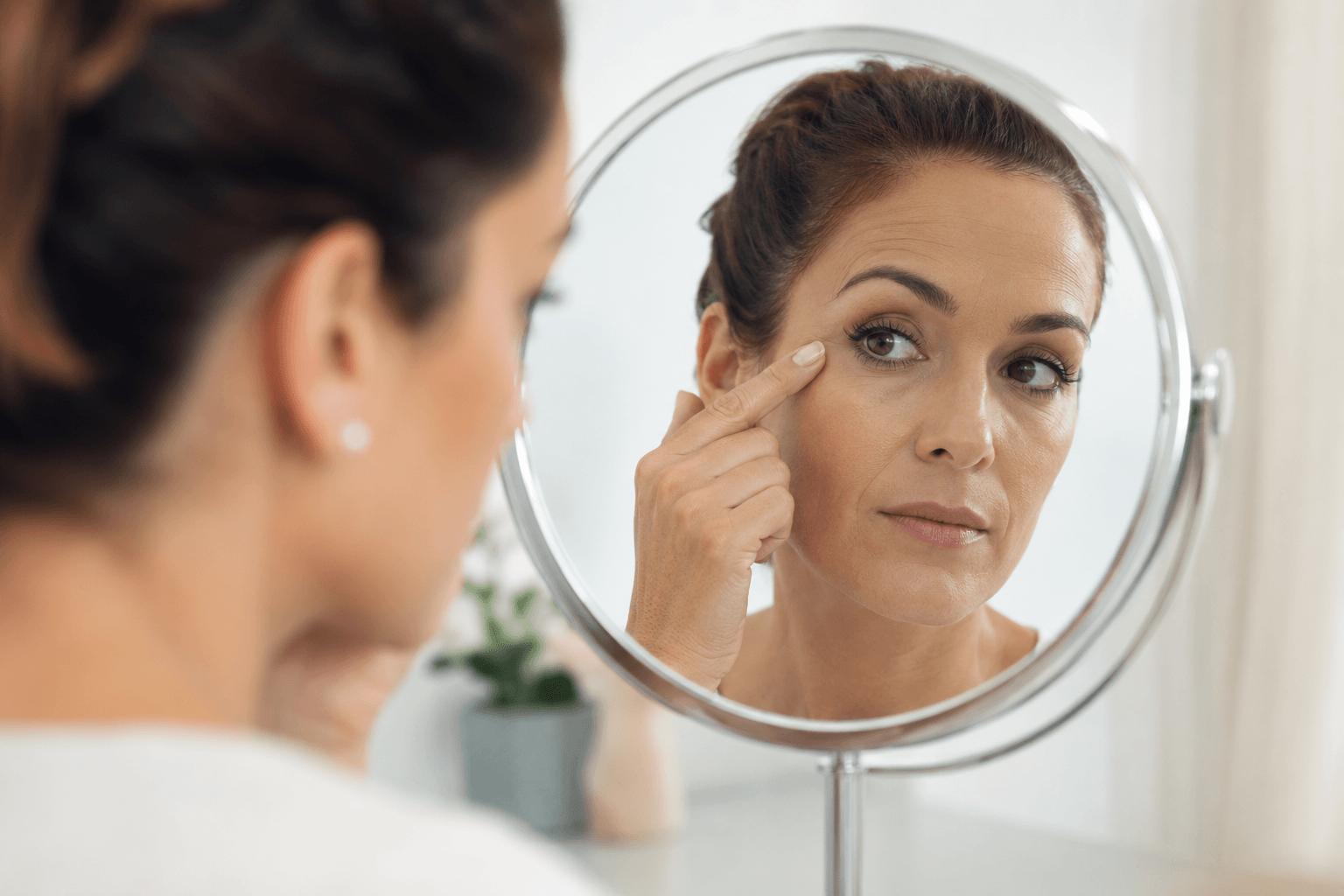 Woman applying foundation with visible fine lines softened after Dysport treatment in Louisville Kentucky