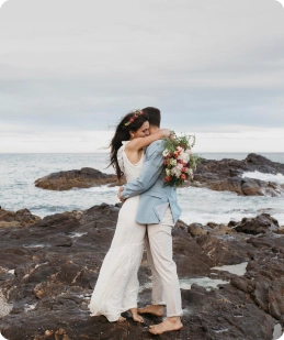 "Bride and groom kissing near ocean waves "