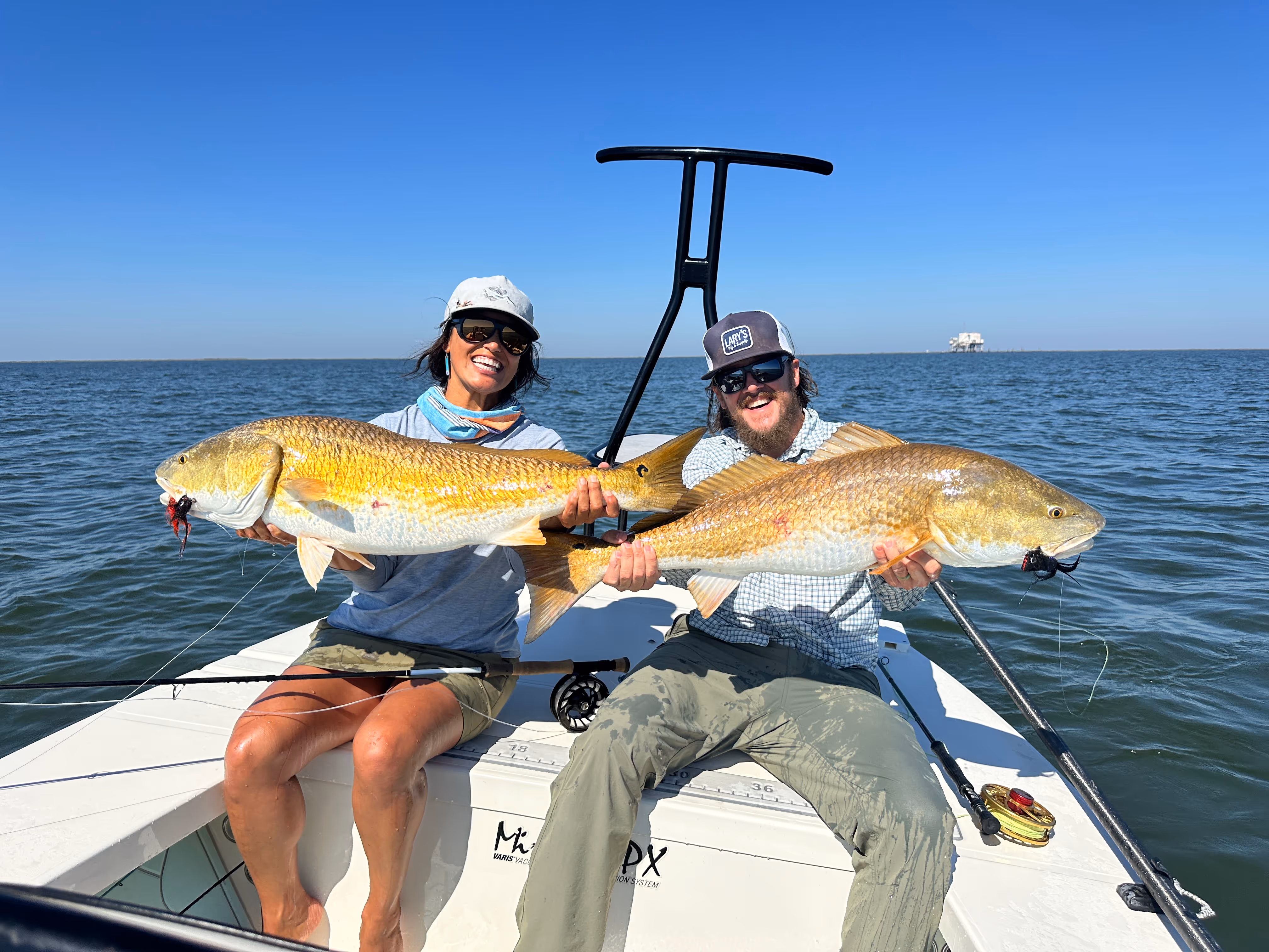 woman and man holding large fish on salt water boat
