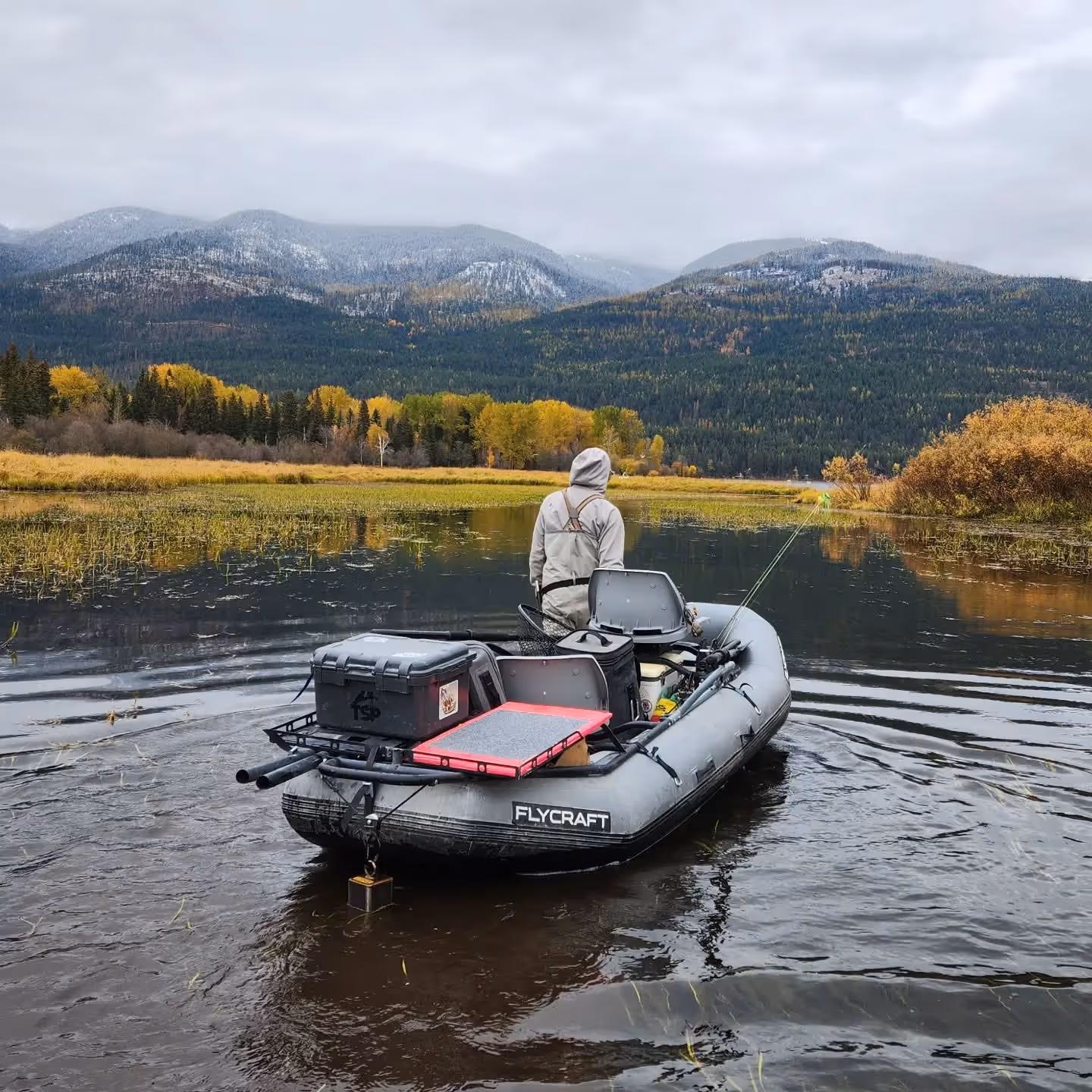 fly fishing angler on lake with mountain view