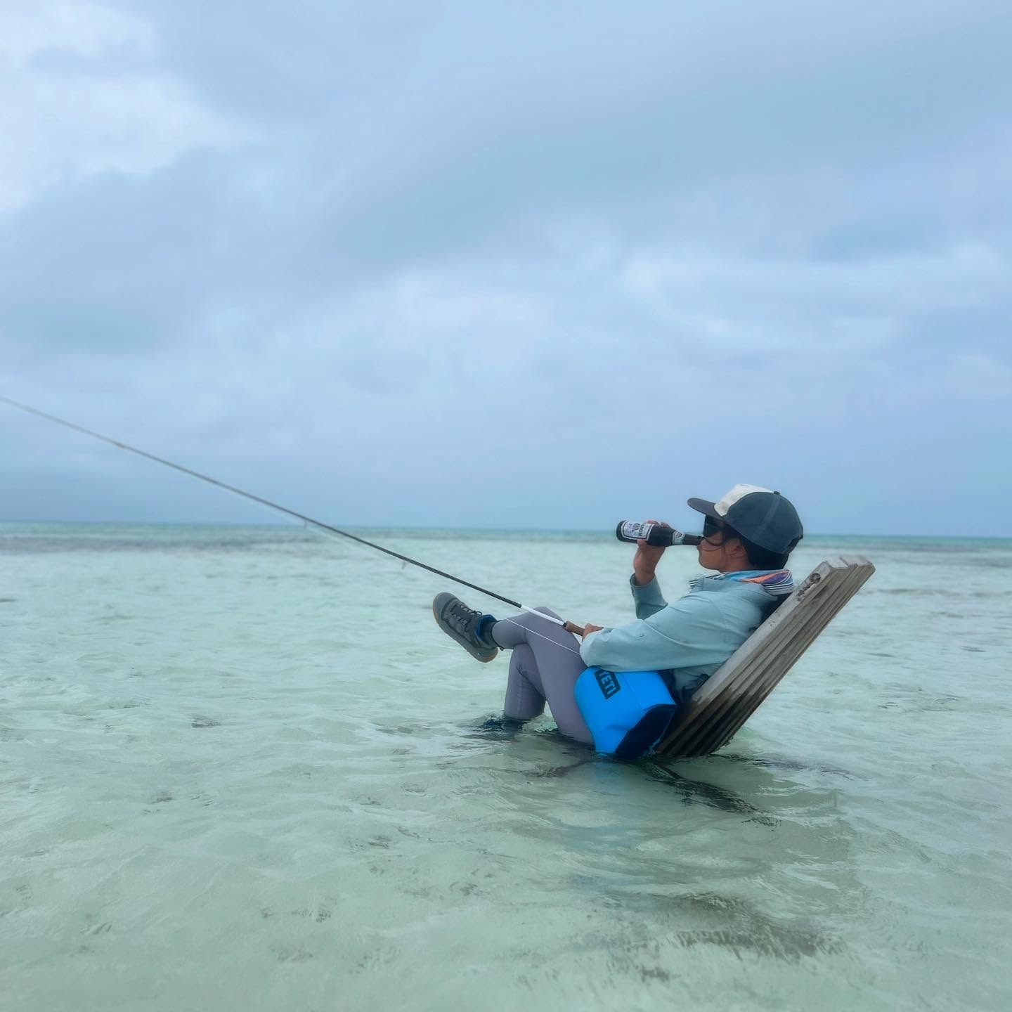 fly fishing woman sitting in chair in ocean