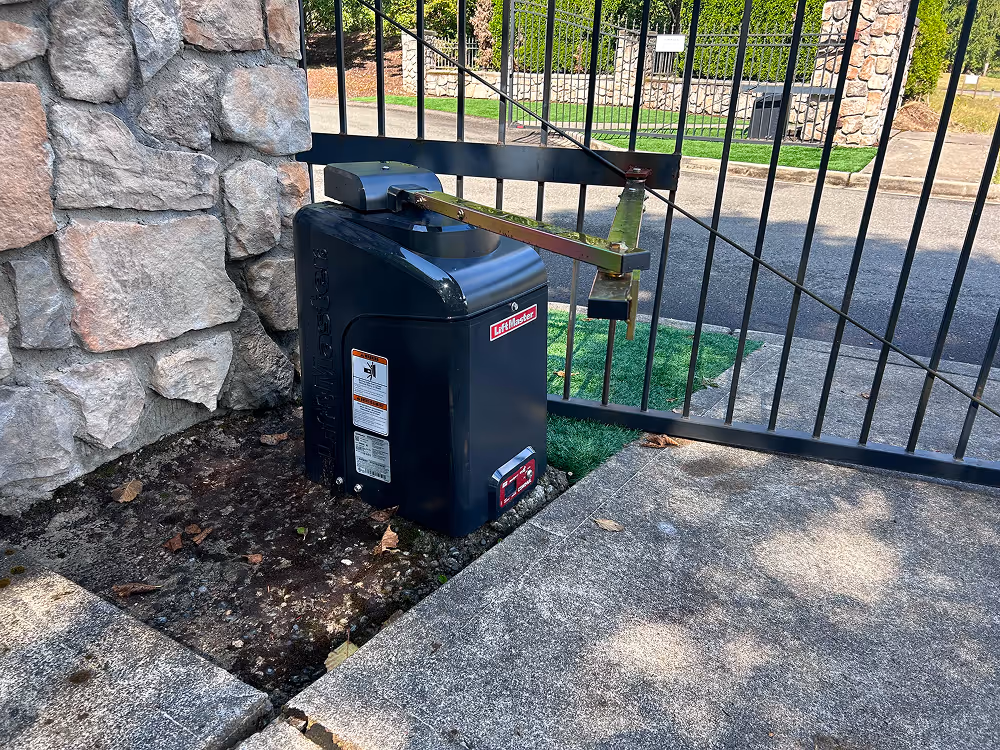 LiftMaster gate opener motor installed next to a black metal gate and stone wall.