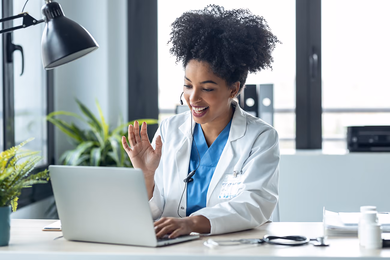 Attractive afro female doctor talking while explaining medical treatment to patient through a video call with laptop in the consultation