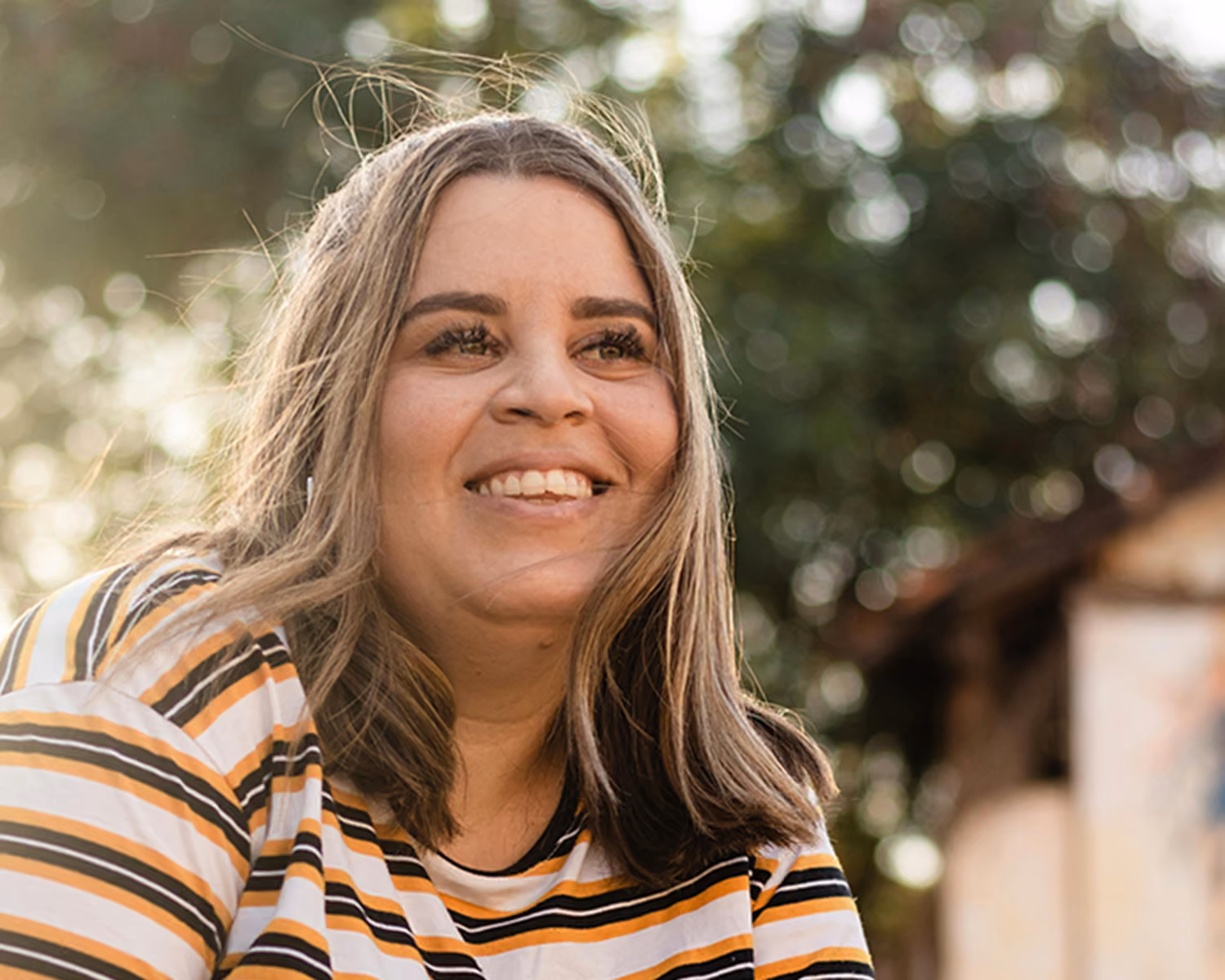 Smiling plus size blonde woman sitting outdoors with the sun shining
