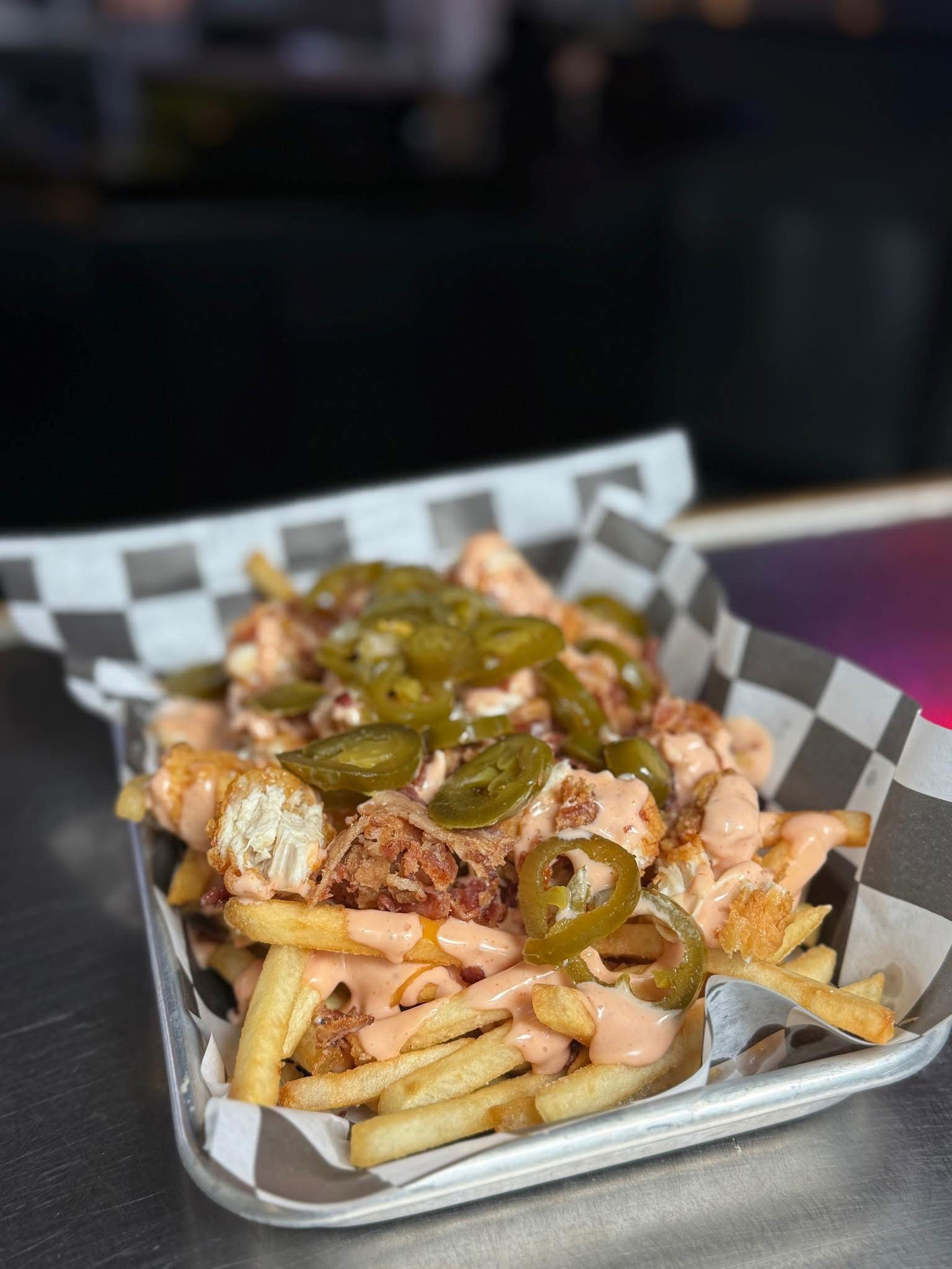 Two trays each with a bacon cheeseburger featuring multiple beef patties and crispy bacon, in a restaurant setting.