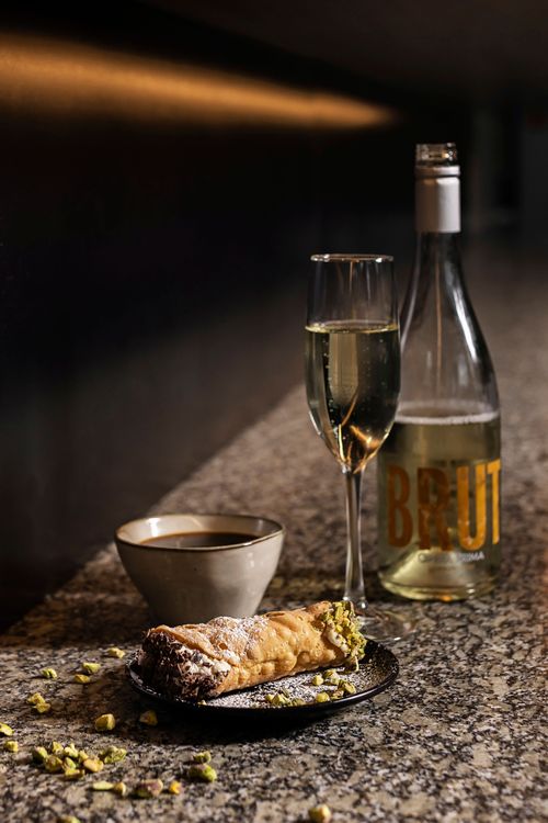 Italian style dessert with cannoli and wine on a modern stone table inside Muse at Benaroya, prepared by DSquared Hospitality chefs