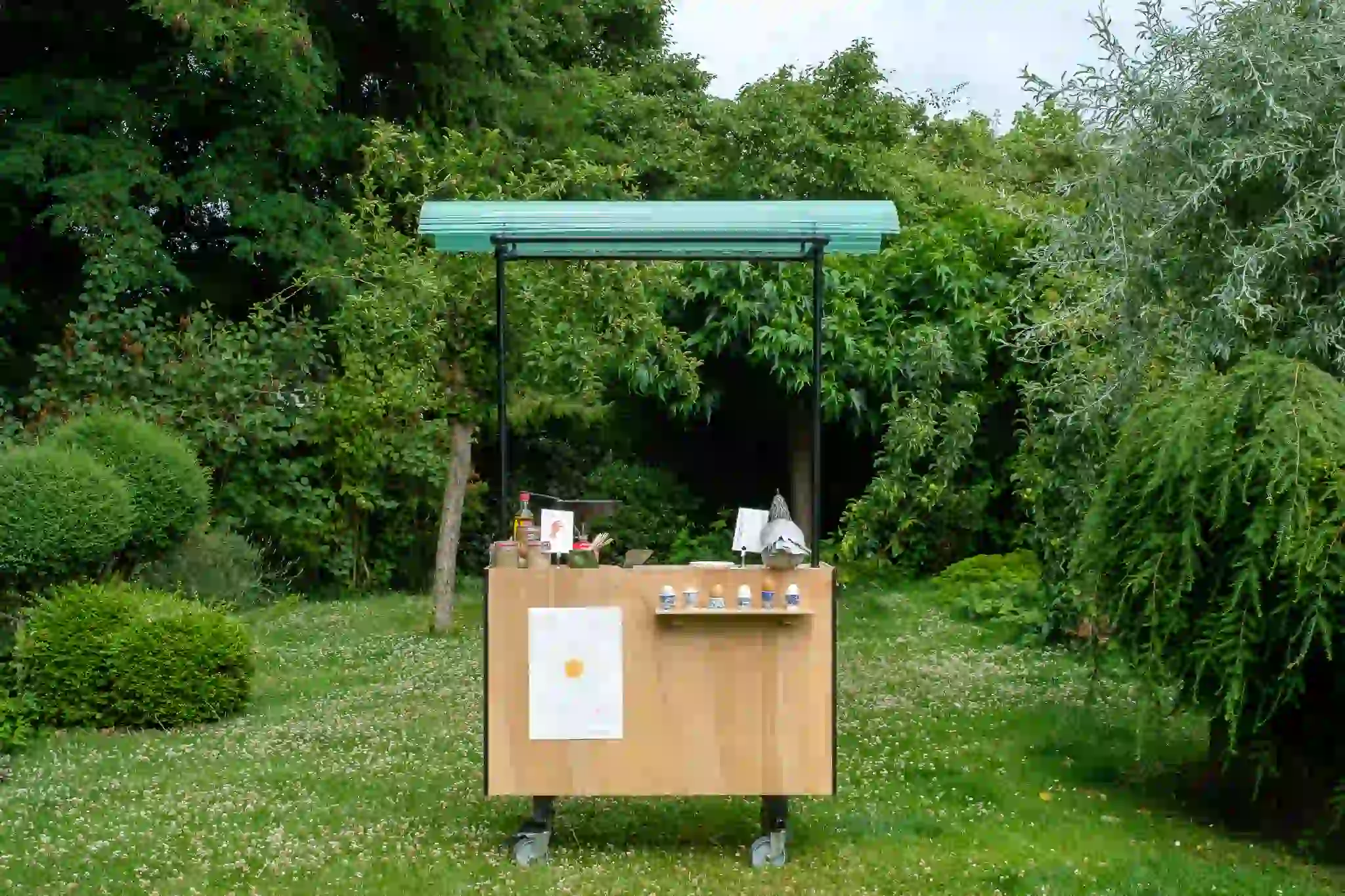 ooden mobile cart with a green roof standing in a lush garden.