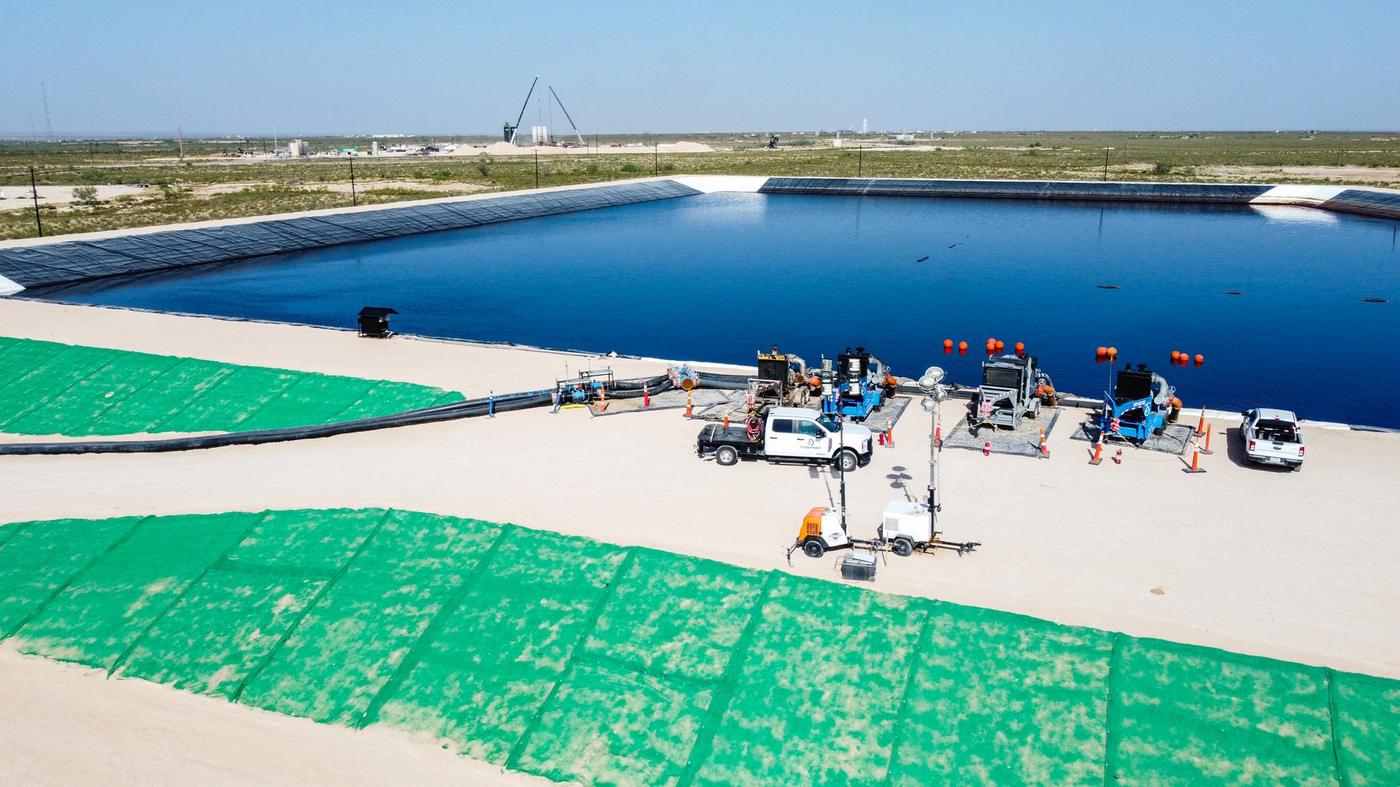 Flowpoint pumps staged on containment mats at the pit edge with light towers