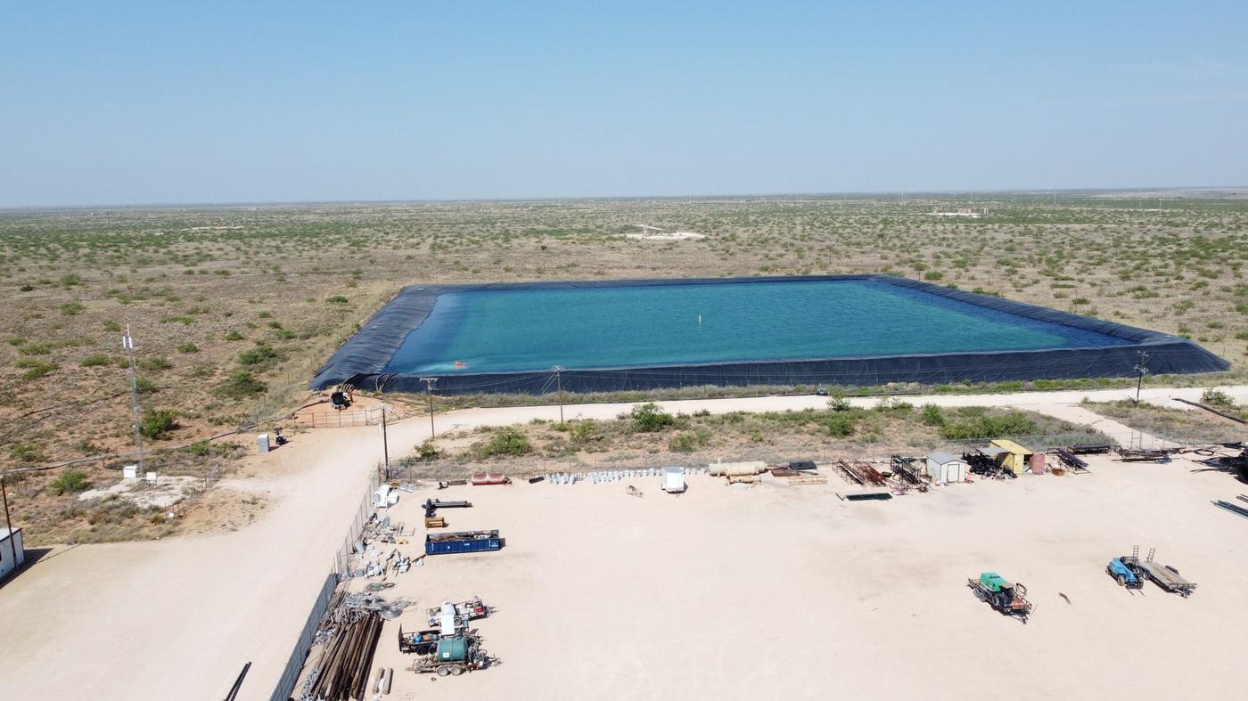 Aerial view of a lined water storage pit and equipment yard in West Texas