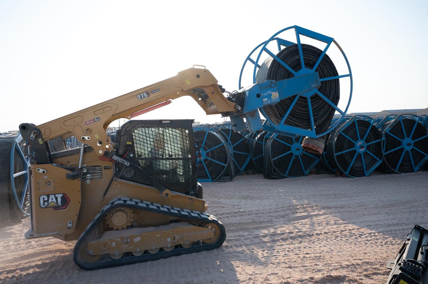 Skid steer handling a layflat hose reel during deployment