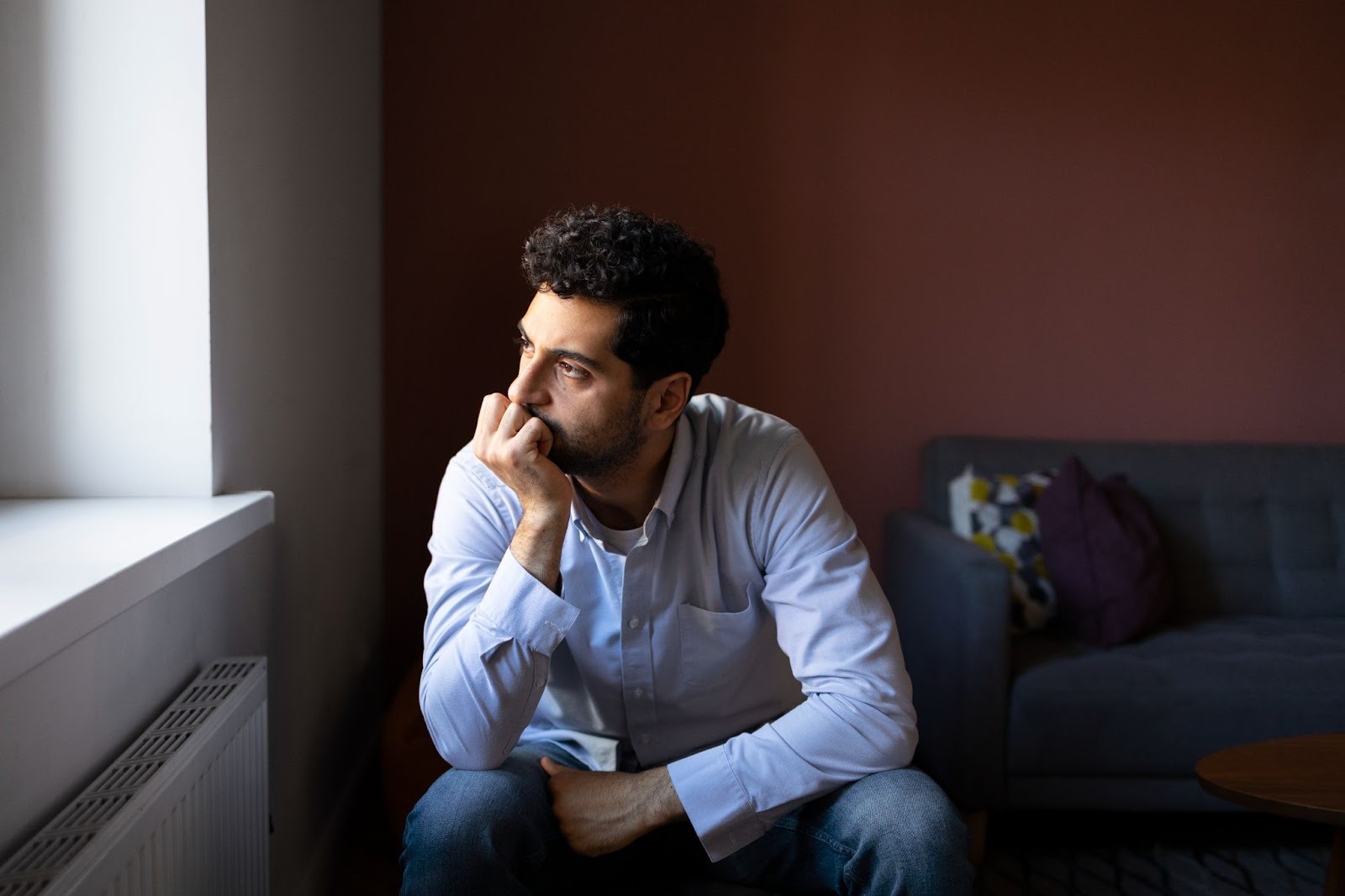 man sitting by a window looking thoughtful representing reflection