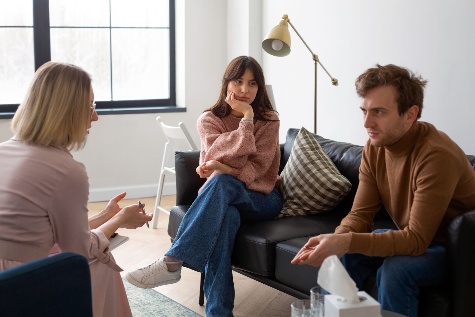 An image of a male and female sitting on a couch and attending a counseling session with a professional
