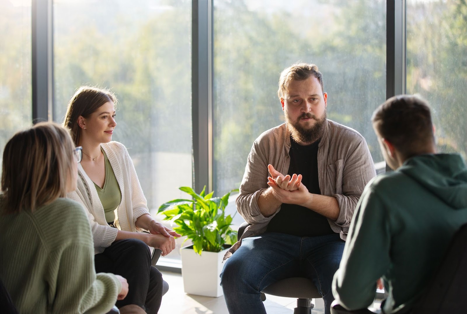 A group of four people comprising two women and men attending a group therapy session