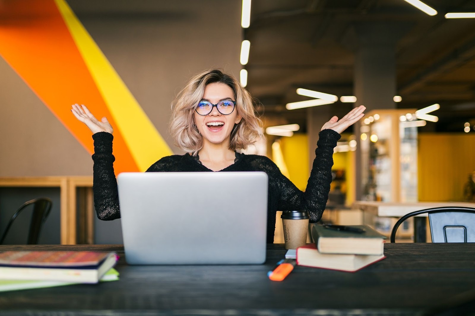  Woman using a laptop at work with books and coffee, representing balancing a job while attending rehab