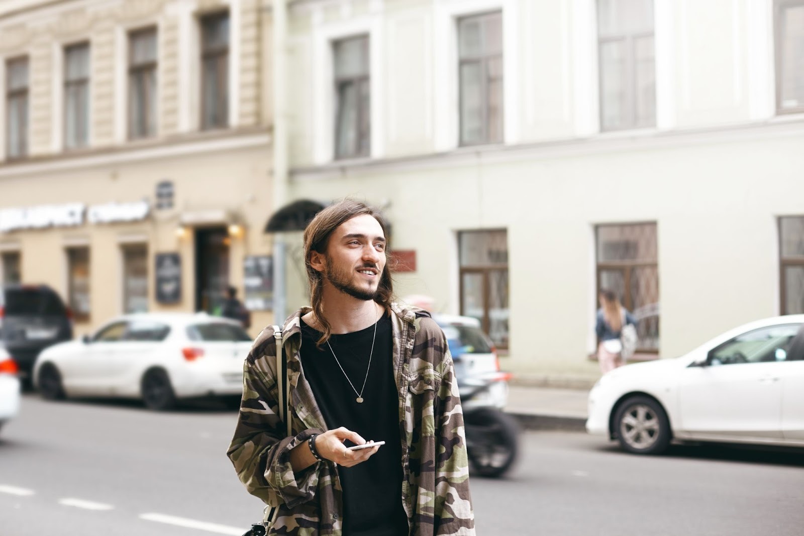 A man in recovery smiles while using his phone on a city street, symbolizing reintegration into daily life after residential rehab