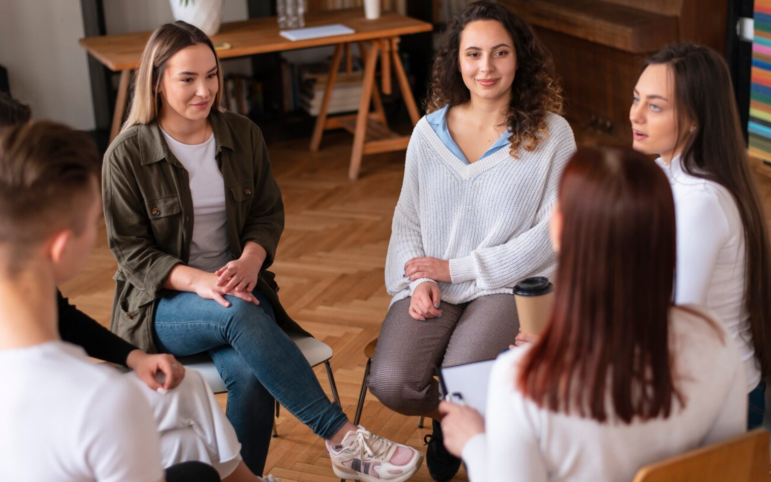 Five individuals participate in a group therapy session at an outpatient program, supporting each other through the transition from residential rehab to HIOP