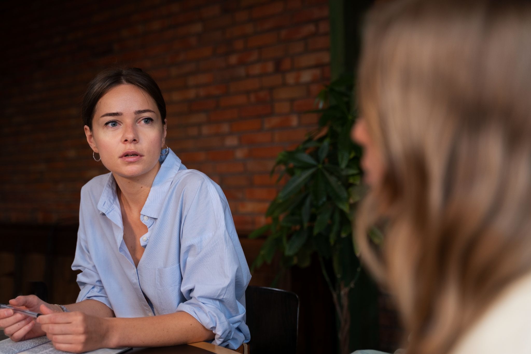 A woman in a counseling session is listening attentively during a one-on-one therapy conversation in an outpatient setting