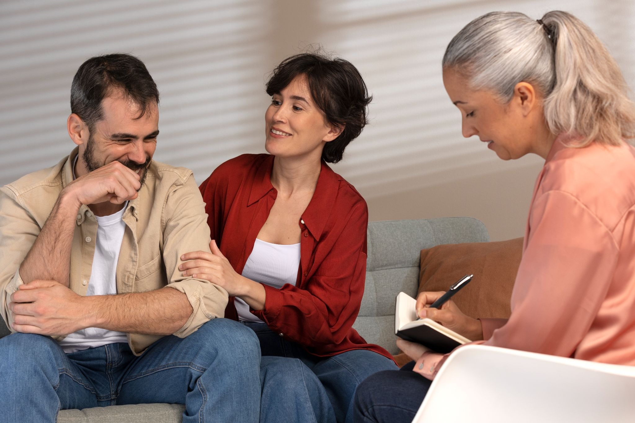 Alt text: A couple sits with a counselor during a supportive therapy session, discussing recovery challenges and family dynamics in a comfortable clinical setting