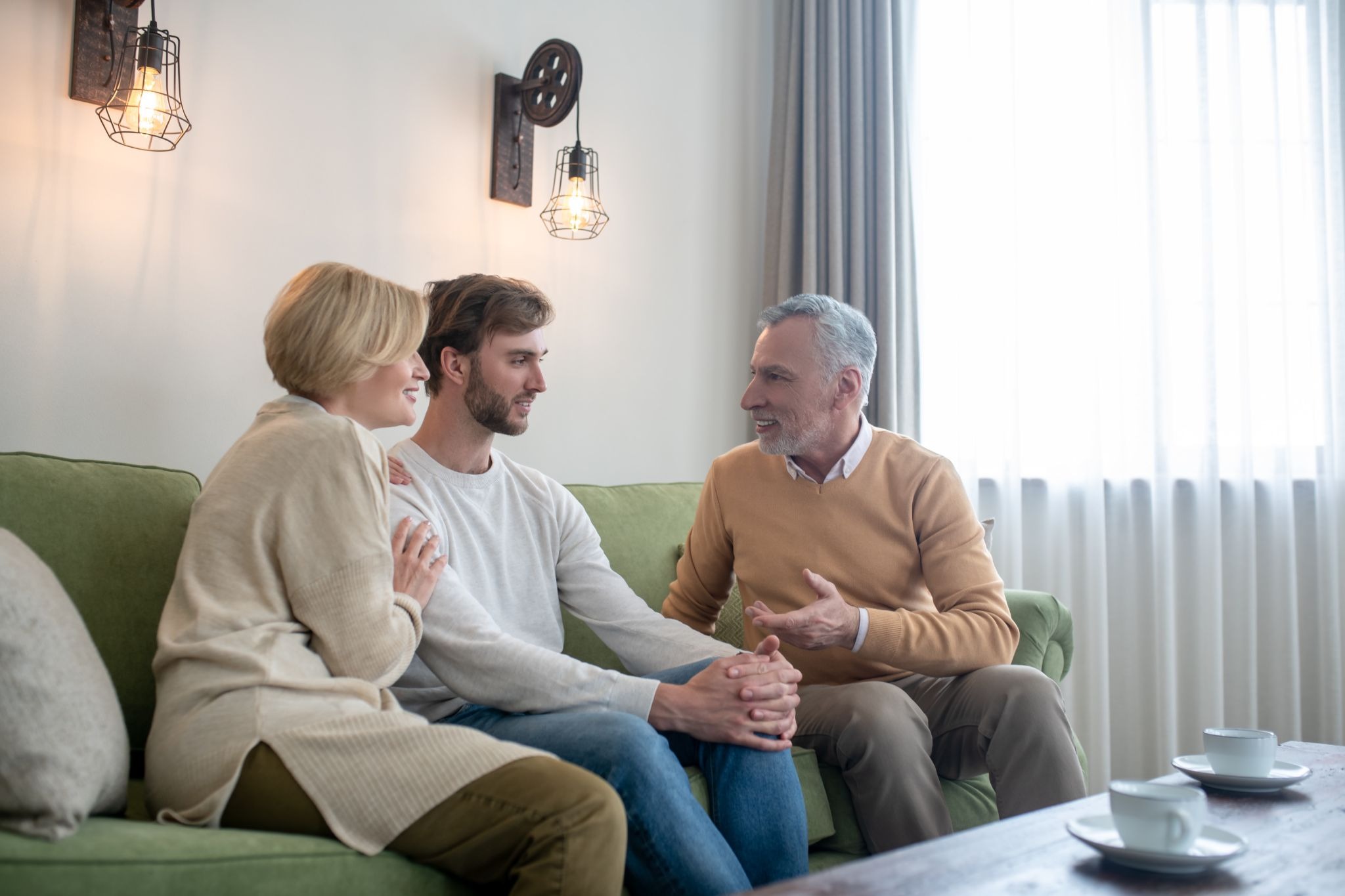 Family members sit together in conversation at home, reflecting emotional support, communication, and the role loved ones can play during addiction recovery and treatment