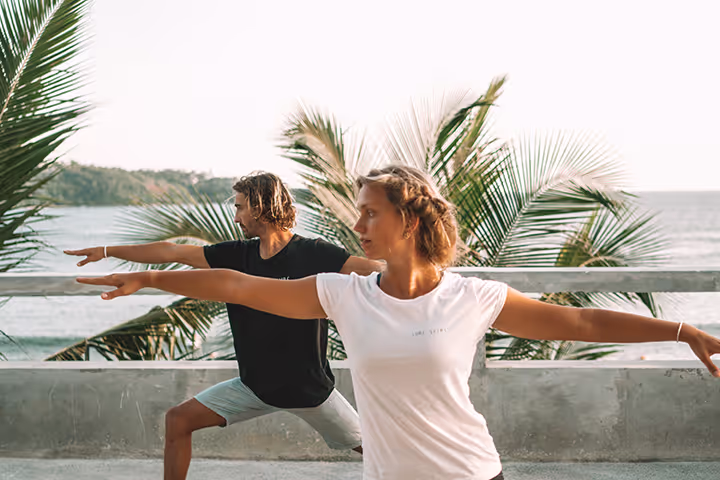 A man and woman are practicing yoga on a patio.