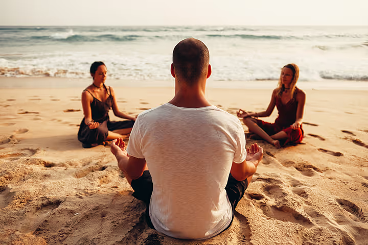 A man sitting on the beach with two women.