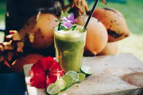 A glass of green smoothie with a flower on top.