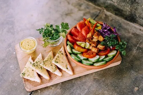 A bowl of vegetables and a plate of bread.