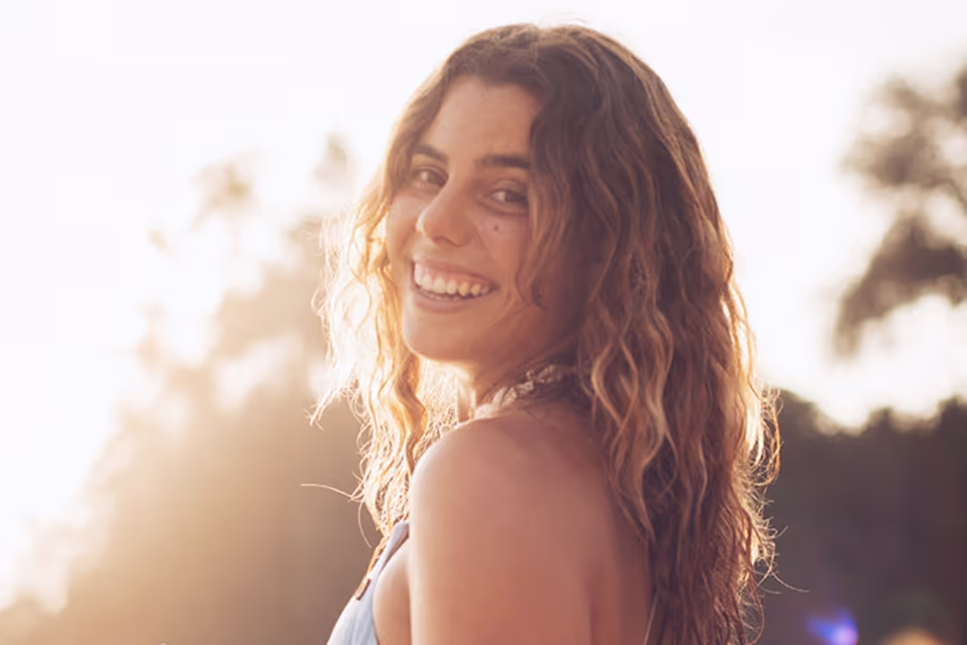 A woman with long hair and a blue tank top smiling at the camera.