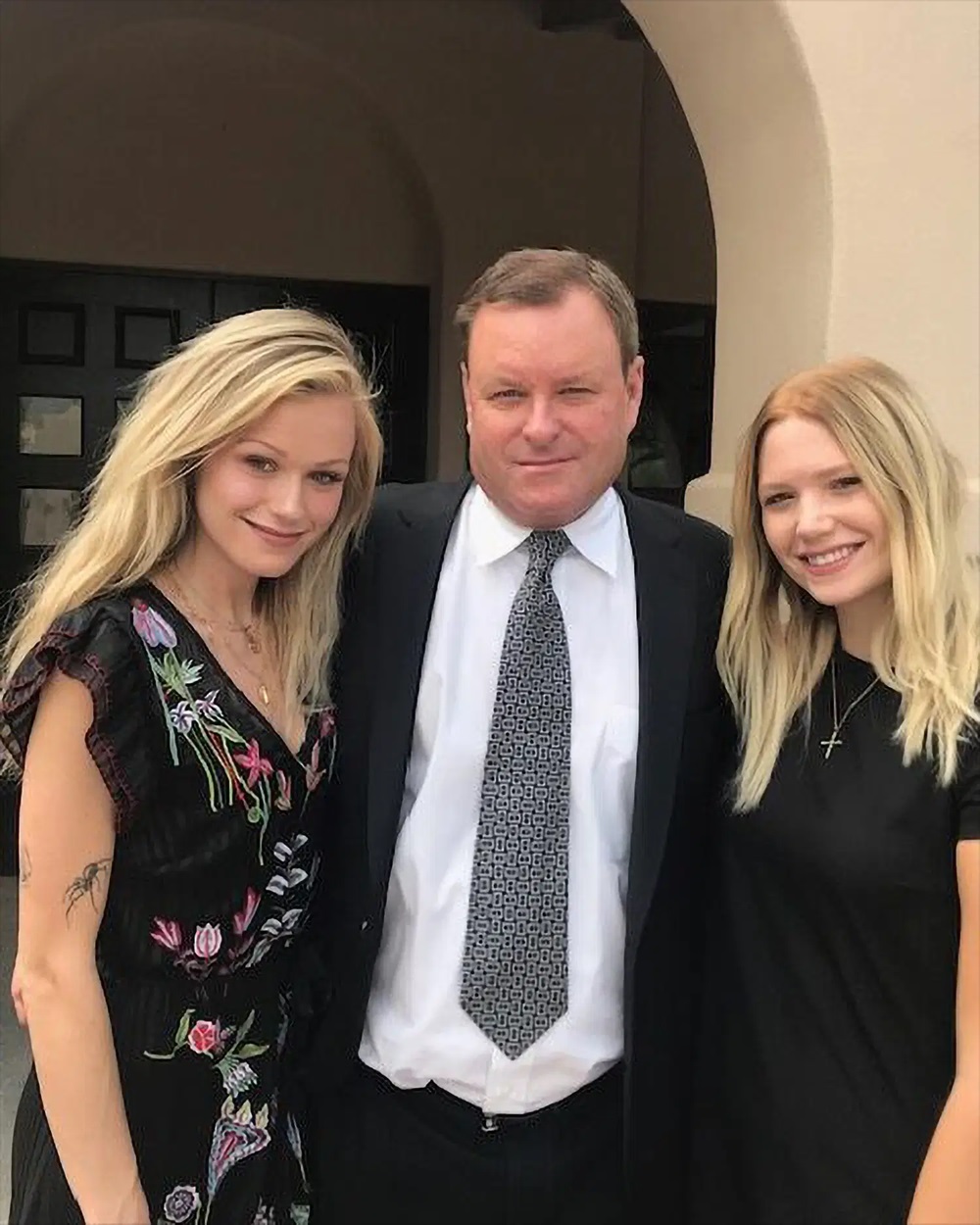 Devin Doyle in formal clothing posing with two family members dressed in dark outfits