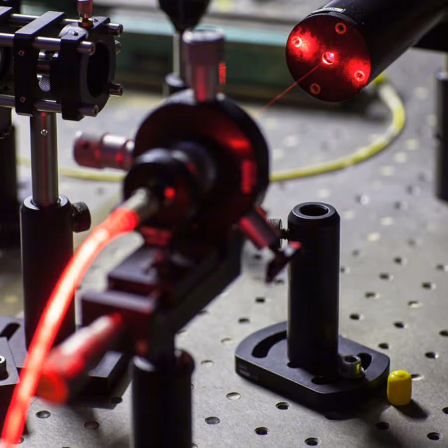 Laser equipment setup with glowing red laser beams on experimental table with mounting components.
