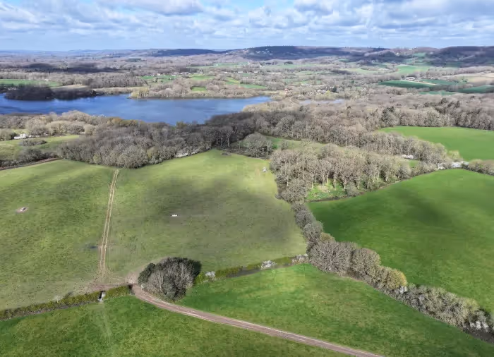 An arial photograph of the Bore Place estate with green fields, lots of trees and a big lake in the distance. 