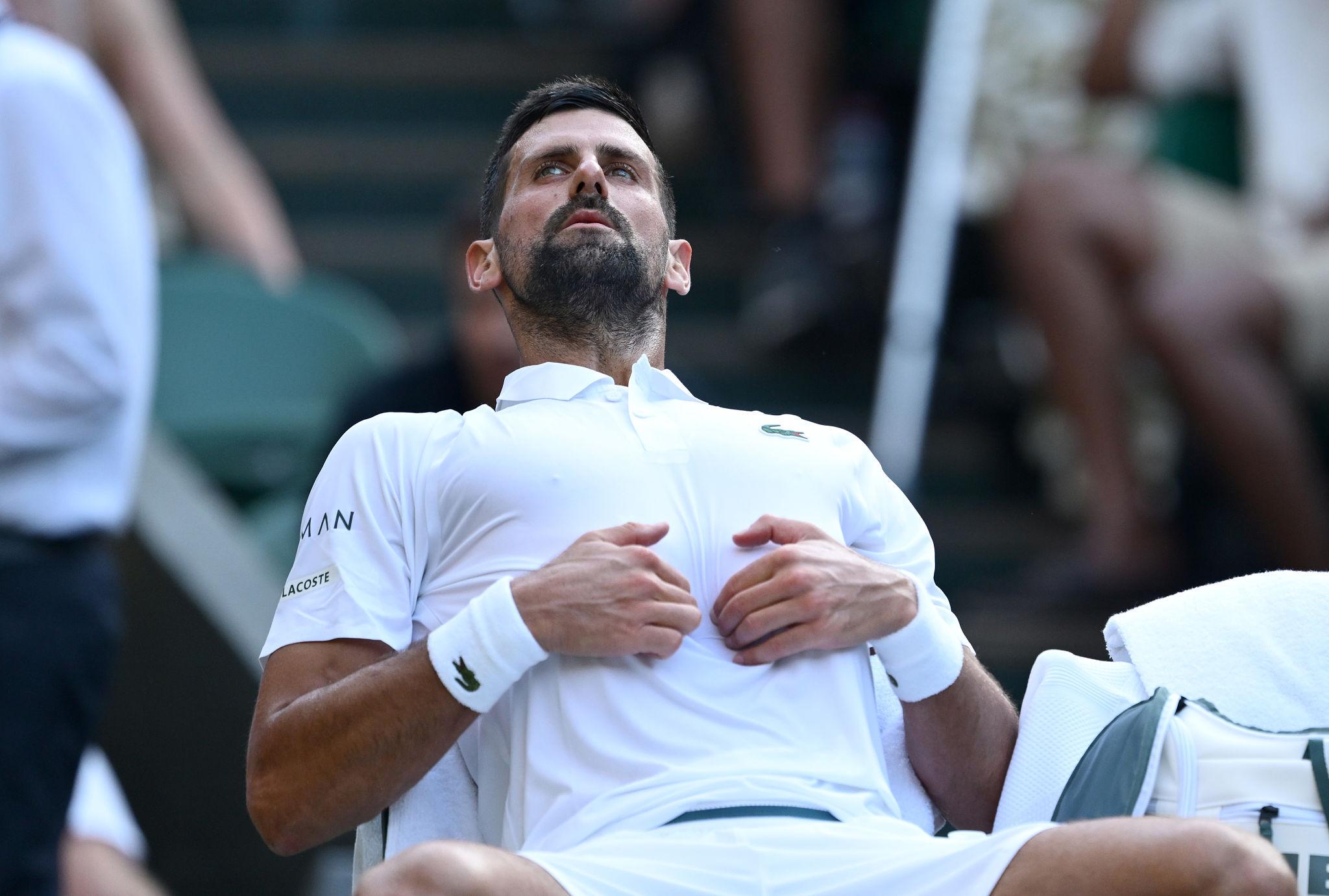 Novak Djokovic massaging his diaphragm and lower rib cage between points during a tennis match.