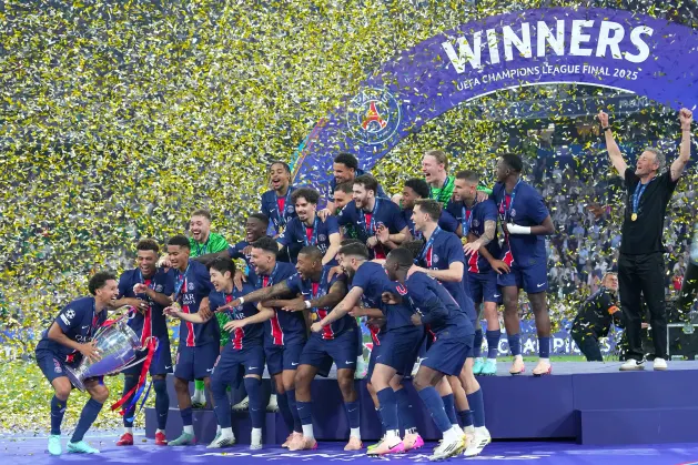 Paris Saint-Germain players celebrating on stage with the UEFA Champions League trophy after winning the 2025 final, surrounded by confetti and a "Winners" banner.