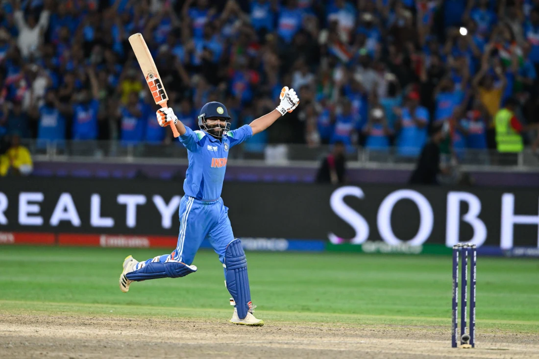 Indian cricket player celebrating a match-winning moment with arms raised, bat in hand, and fans cheering in the stadium, showcasing sponsor logos on the uniform as a highlight of sports sponsorship activation and fan engagement.