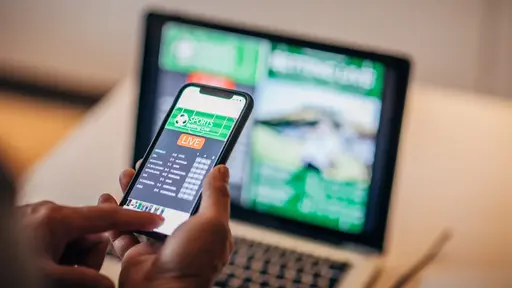 Dakar Rally truck podium ceremony with winning teams celebrating and holding trophies in front of a large Dakar Rally logo and an orange race truck.