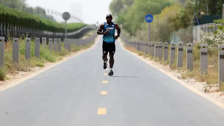 Endurance athlete Ghani Souleymane running on a Dubai road during his 100-day T100 triathlon Guinness World Record attempt, demonstrating sports sponsorship and talent representation.