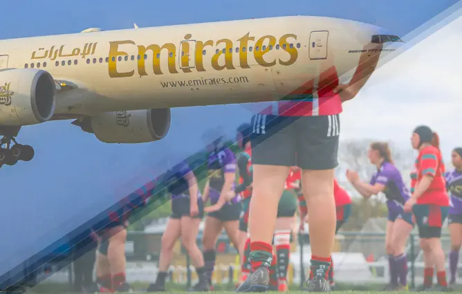Close-up of an Emirates airplane flying low above a women's rugby team during a match, highlighting Emirates’ global sports sponsorship presence and connection to both aviation and sporting events.