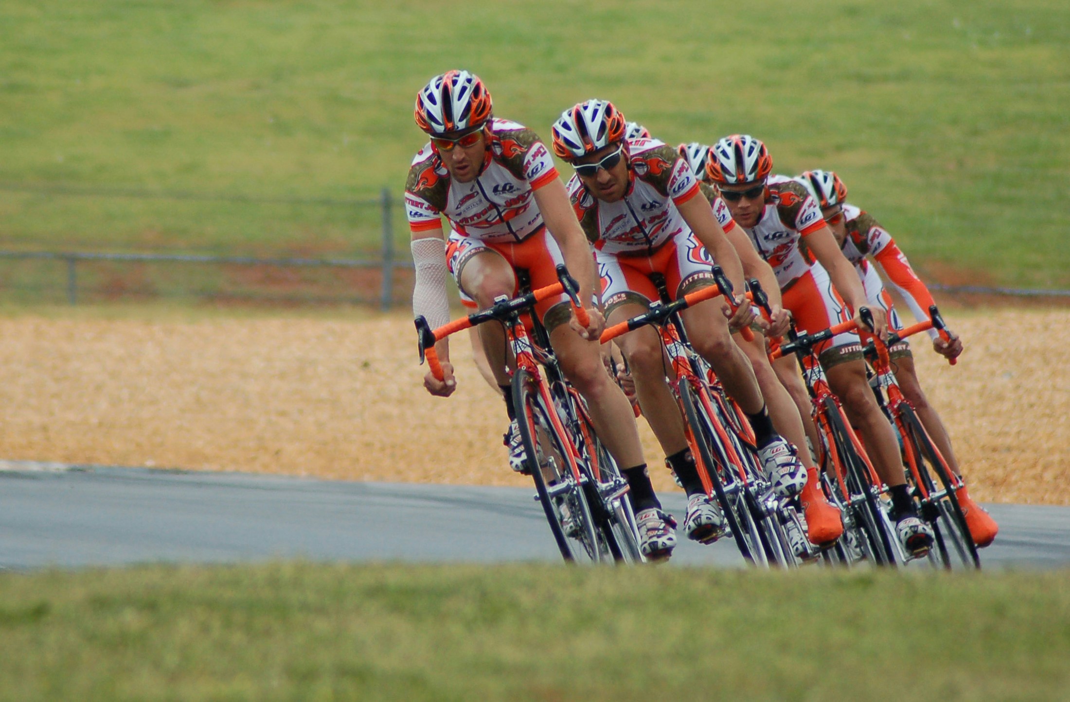 Professional cycling team in matching uniforms riding closely together on a race track, demonstrating teamwork, endurance, and coordinated strategy in competitive cycling.