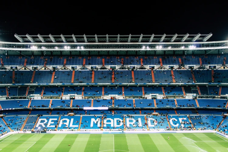Panoramic view of Santiago Bernabéu Stadium with empty blue seats displaying 'REAL MADRID C.F.', home of world-famous football club Real Madrid, ahead of a match, highlighting premier sports venue atmosphere and international football culture.