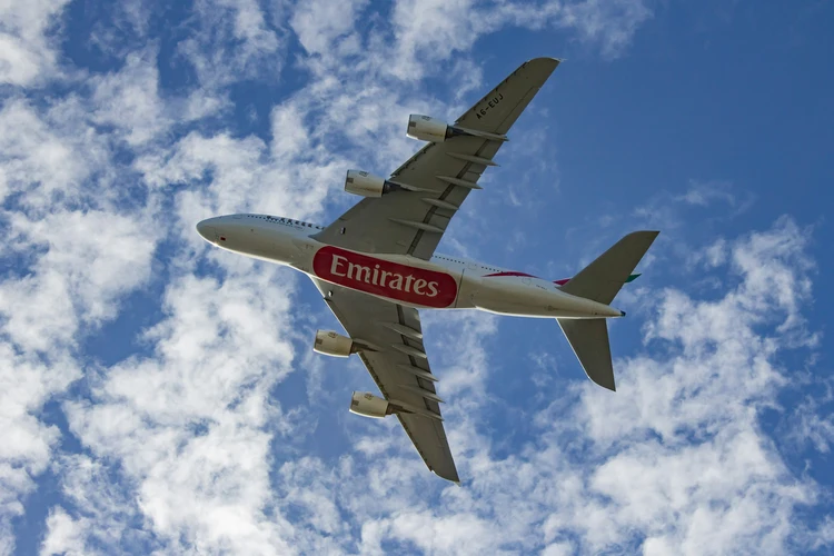 Emirates Airbus A380 flying overhead against a blue sky with clouds, showcasing global event sponsorship and prominent airline branding in international sports and travel marketing.