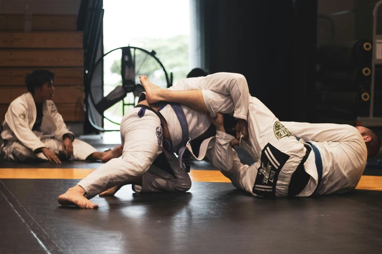 Jiu-jitsu athletes compete in a grappling match, highlighting talent representation and skill development on the mat.