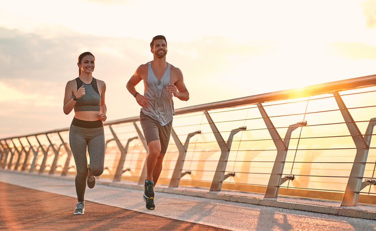 Two athletic runners enjoying an outdoor workout at sunrise on a modern Dubai bridge, illustrating healthy lifestyles connected to event sponsorship.