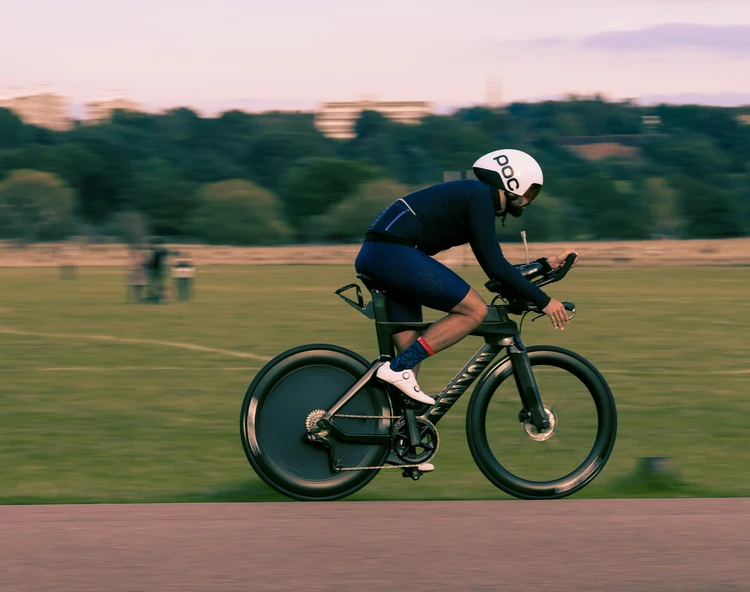 Athlete cycling on a time trial bike in a triathlon event, showcasing personal branding through competitive performance and sport in an outdoor setting.