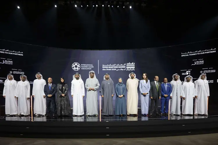 Group photo of executives signing strategic event sports sponsorships for Open Masters Games Abu Dhabi 2026, with IMGA and Abu Dhabi Sports Council logos on stage.