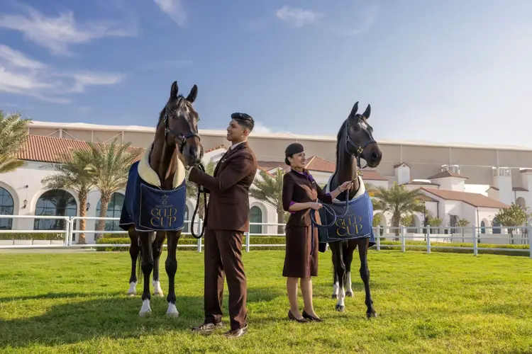 Etihad Airways Abu Dhabi Gold Cup event sponsorship: Etihad reps in uniforms with horses wearing blue Etihad blankets at Abu Dhabi Turf Club, highlighting official partnership.