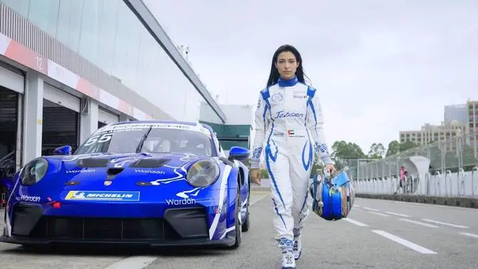 Amna Al-Qubaisi poses in her Team Jebsen Wardah-liveried Porsche 911 GT3 Cup suit beside the blue race car at Shanghai track, showcasing elite Talent Representation.
